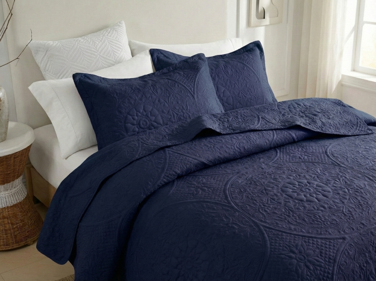 Navy blue quilted bedding set on a bed with white pillows in a bedroom setting.