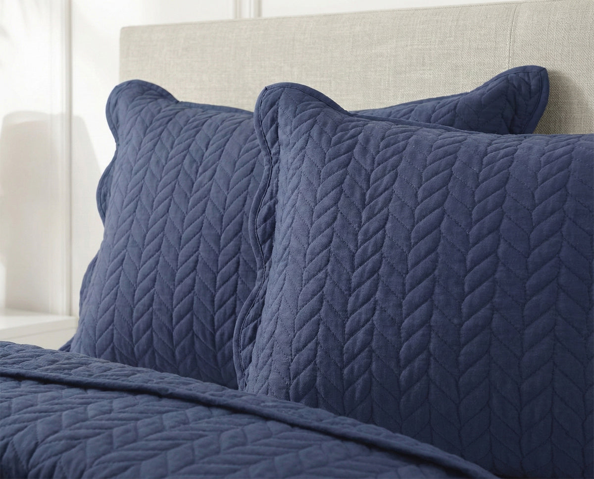 Navy blue quilted cotton pillows and bedding with chevron pattern on bed