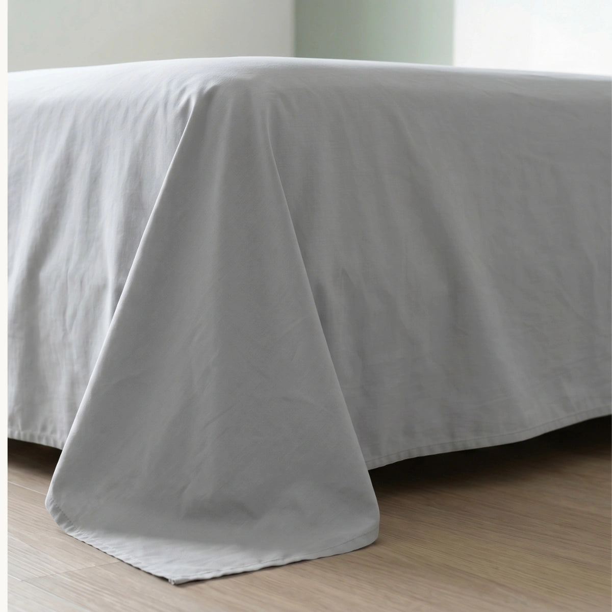 Cloud Grey cotton bedsheet draping naturally over bed corner showing fabric weight and generous sizing

