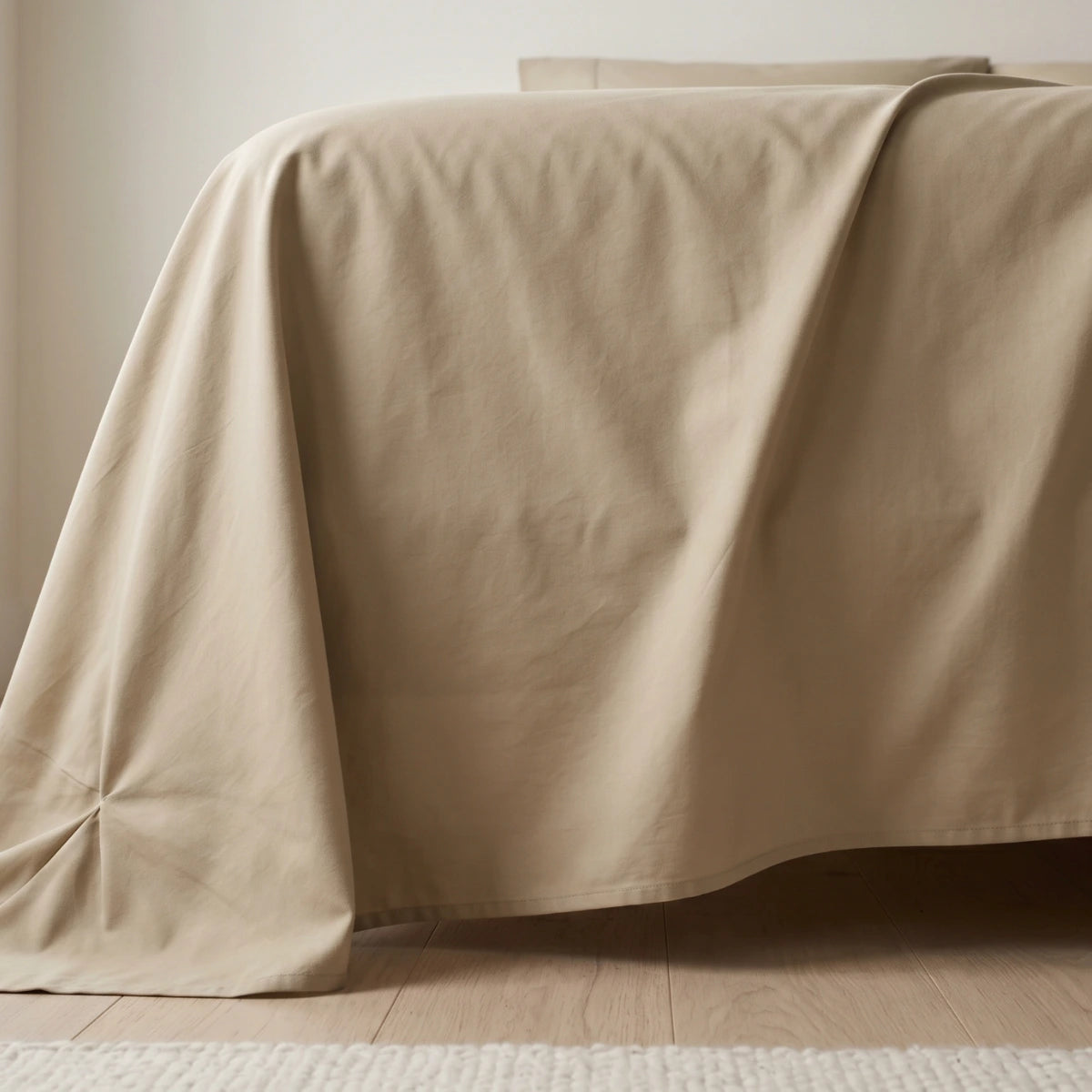 Ivory Sand Beige cotton bedsheet draping naturally over bed corner showing fabric weight and generous sizing