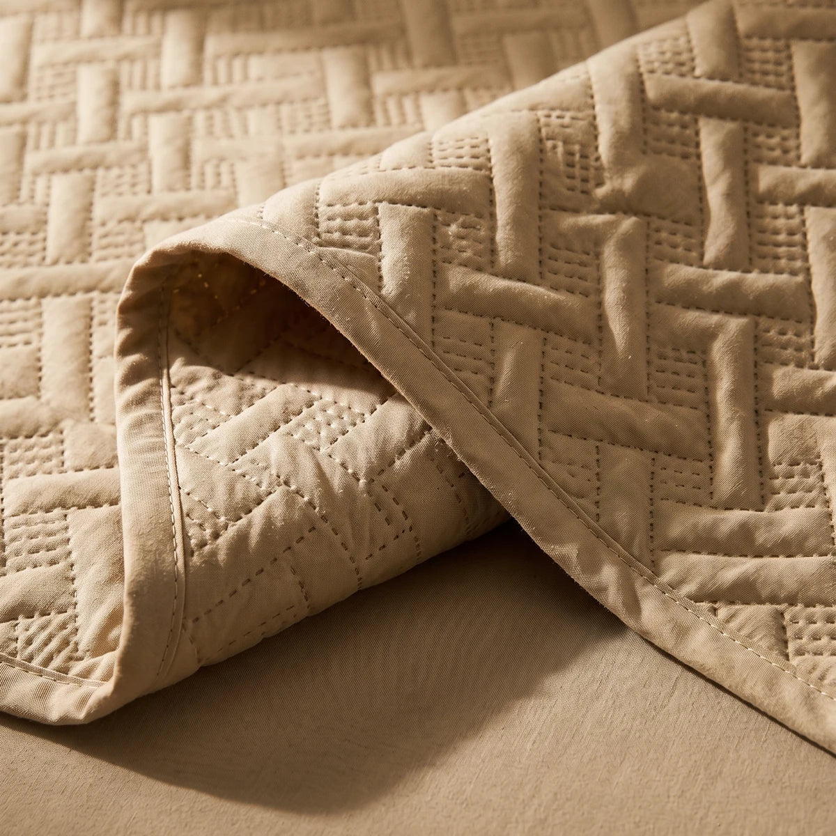 Close-up of embossed woven lattice pattern and stitch detail on almond beige microfiber bedspread