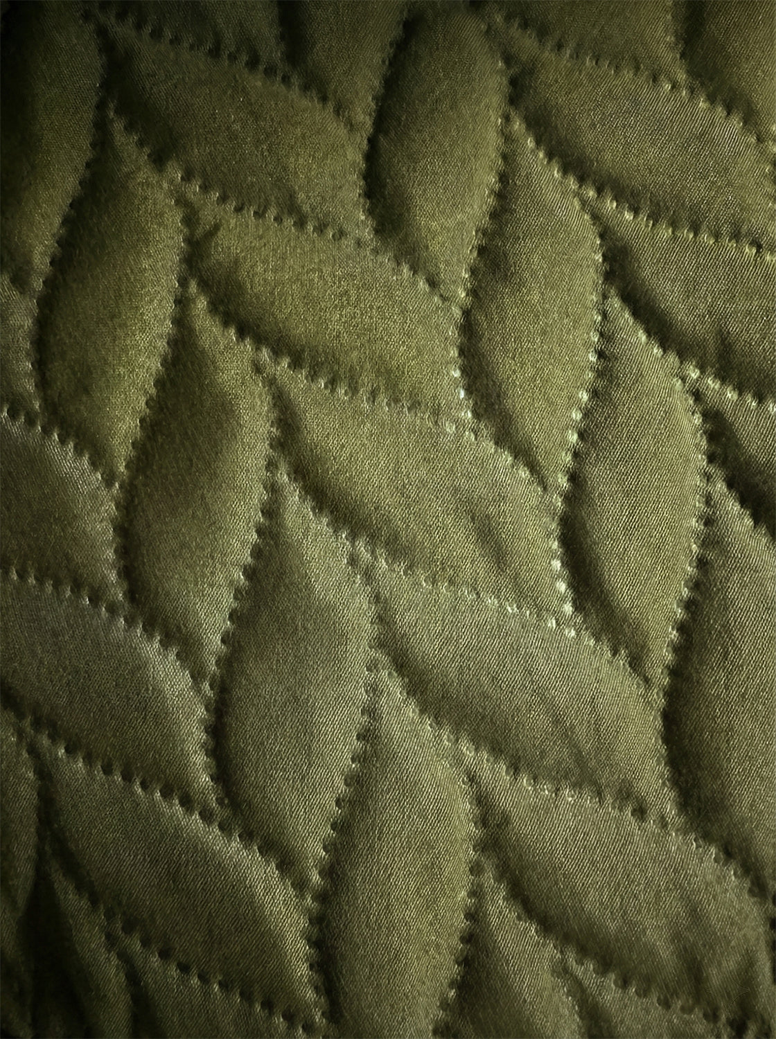 Olive green quilted fabric with a leaf pattern texture, premium bedding textile