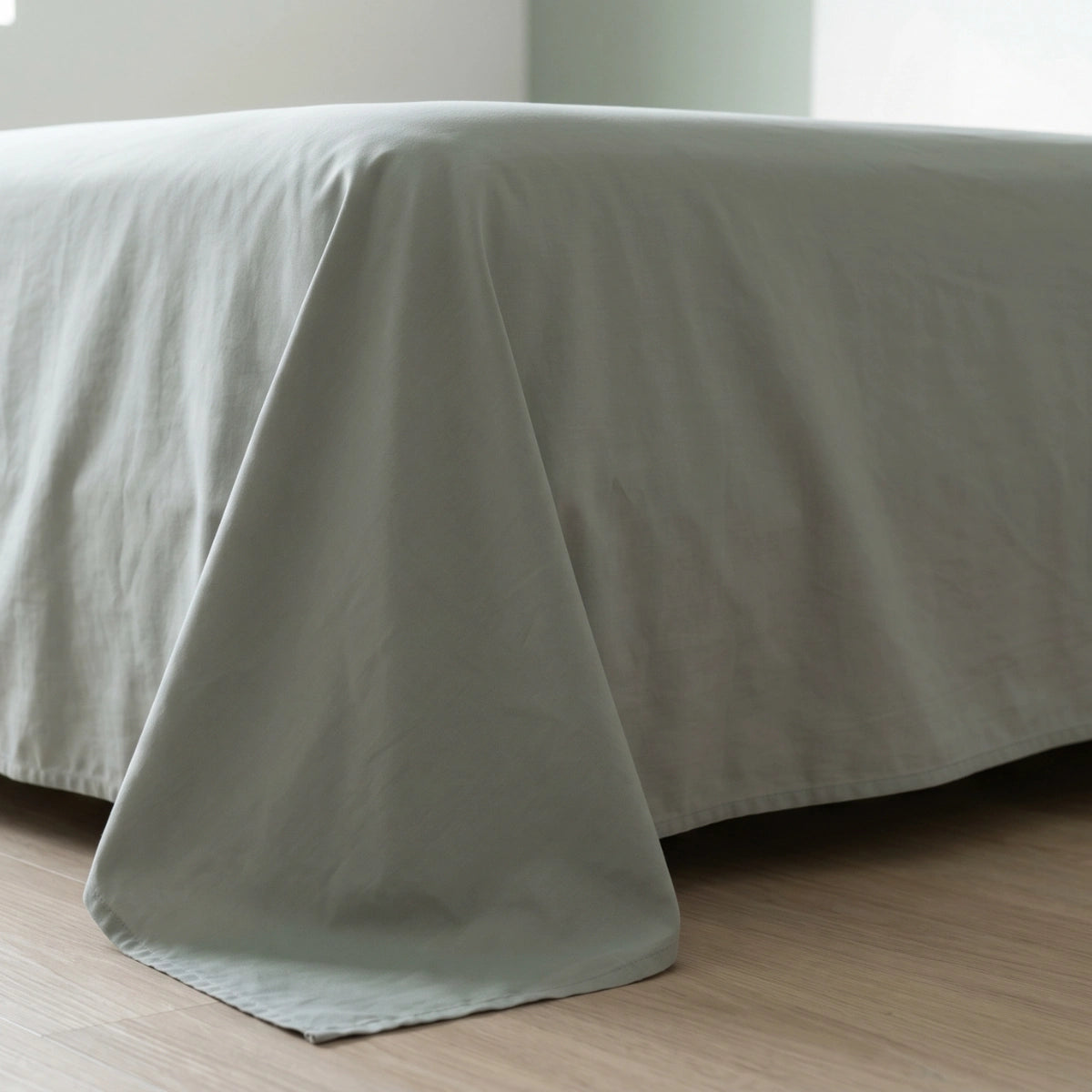 Sage Mist Green cotton bedsheet draping naturally over bed corner showing fabric weight