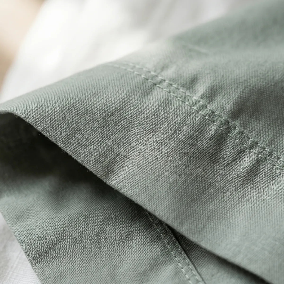 Close-up of Sage Mist Green T200 cotton percale fabric weave and hemstitch detail